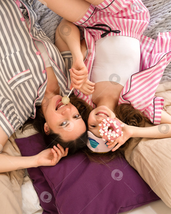 Скачать Мать и дочь наслаждаются сладостями в одинаковых пижамах. фотосток Ozero