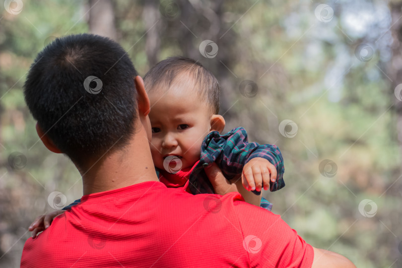 Скачать Папа держит своего маленького сына на руках, прогуливаясь по парку. фотосток Ozero