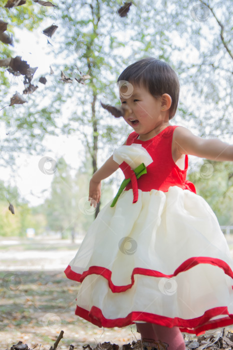 Скачать 5-летняя девочка весной играет с листьями в парке. фотосток Ozero