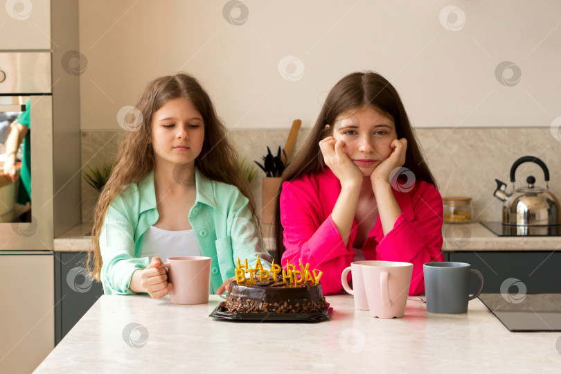Скачать Две девушки сидят на кухне с праздничным тортом и кружками. фотосток Ozero
