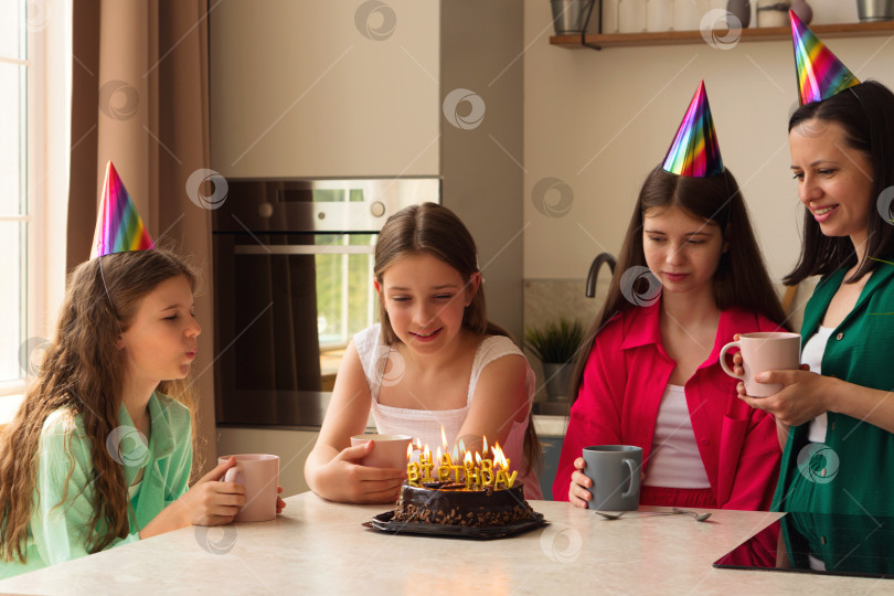 Скачать Семья празднует день рождения молодой девушки с тортом и праздничными шляпками фотосток Ozero