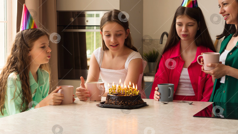 Скачать Девушка задувает свечи на праздничном торте в окружении семьи. фотосток Ozero