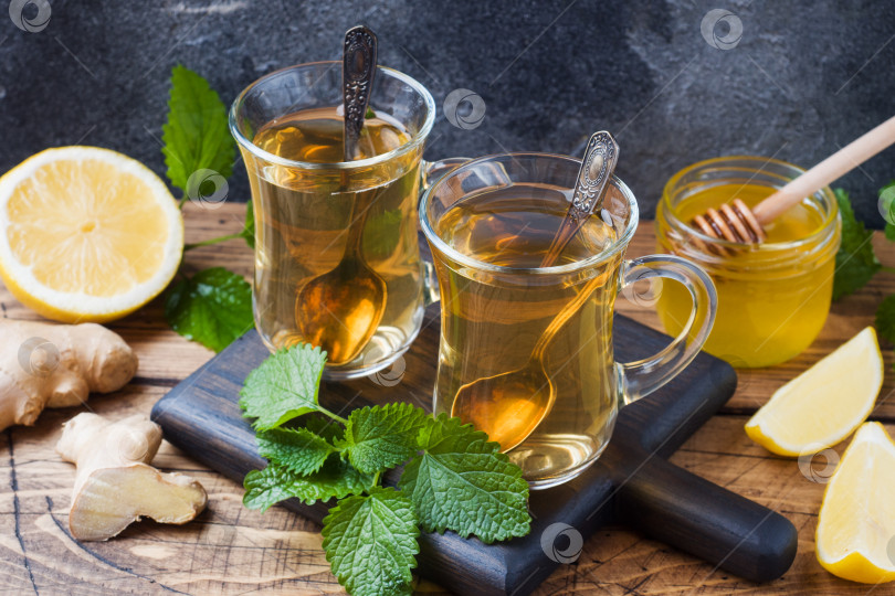 Скачать Две чашки натурального травяного чая с имбирем, лимоном, мятой и медом на деревянном фоне. фотосток Ozero