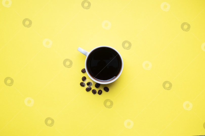Скачать Черный кофе в чашке и кофейные зерна на желтом фоне. Вид сверху на пространство для копирования. фотосток Ozero