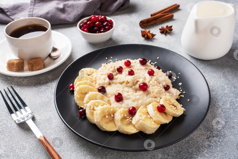 Скачать Овсяная каша на молоке с бананом, клюквой и кунжутом. Чашечка кофе - концепция здорового завтрака. фотосток Ozero