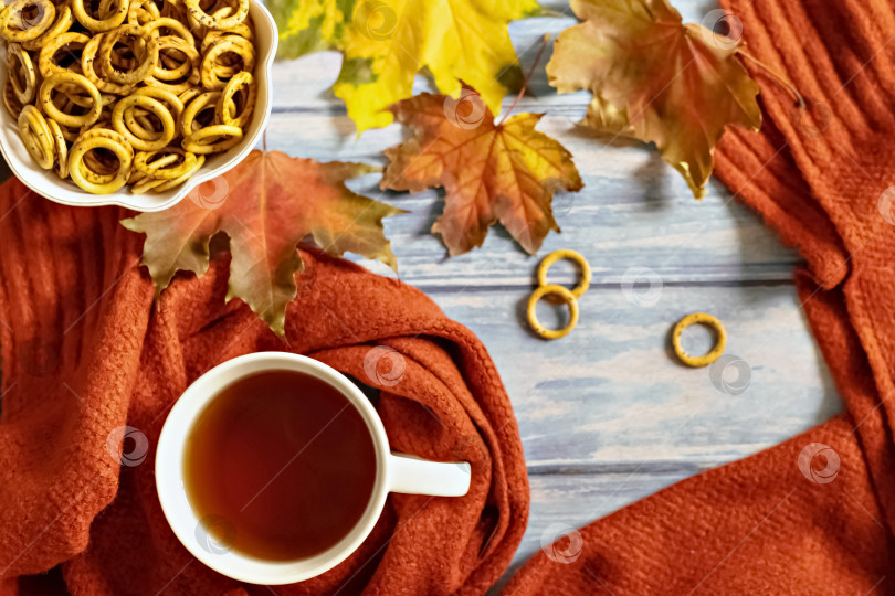 Скачать Осенняя композиция, чашка горячего чая, теплый терракотовый шарф, опавшие листья и сушка на фоне синего деревянного стола. Плоское лежание фотосток Ozero