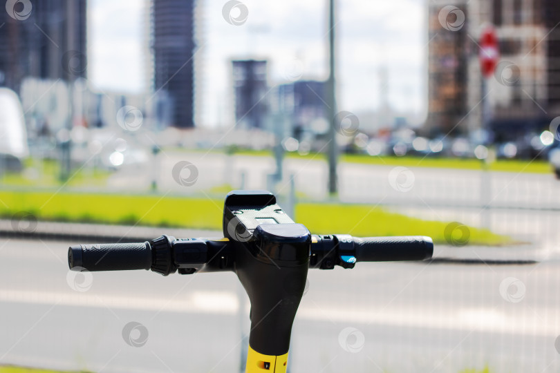Скачать Желто-черный скутер с велосипедным рулем, припаркованный на городской дороге фотосток Ozero