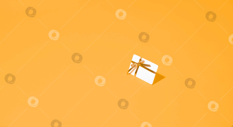 Скачать красиво упакованная подарочная карта с золотой лентой на ярком желтом фоне, символизирующая заветные моменты и особые случаи, которые подарки помогают отпраздновать. фотосток Ozero