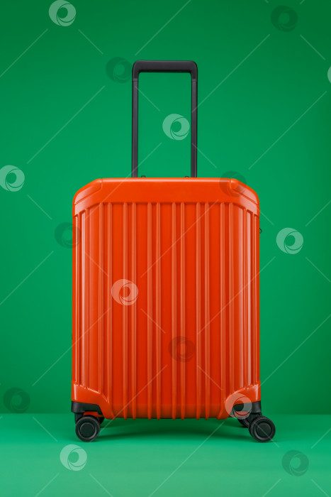 Скачать Дорожный чемодан оранжевого цвета на зеленом фоне фотосток Ozero