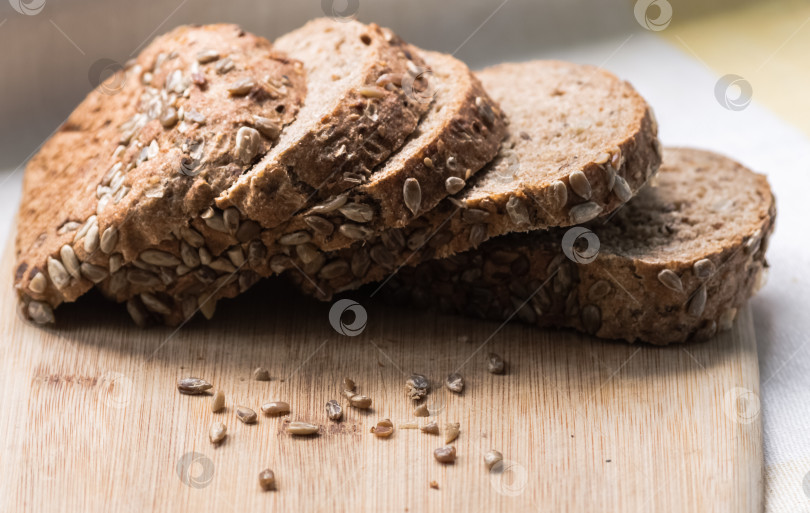 Скачать Нарезанный ломтиками ржаной хлеб с семенами подсолнечника на разделочной доске фотосток Ozero