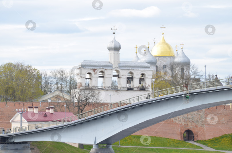 Скачать Великий Новгород, Россия - 13.05.2024: Вид на Кремль Великого Новгорода: Государственный собор (правительственный храм XI века), именуемый Государственным собором , крепкие стены, Горбатый мост фотосток Ozero