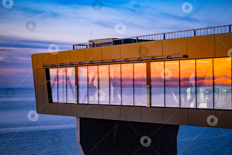 Скачать Светлогорск, Россия - 02 мая 2022 года: Панорамный стеклянный лифт, отражение заката в стеклах фотосток Ozero