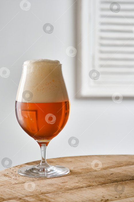 Скачать Бокал янтарного пива на деревянном столе у окна со ставнями фотосток Ozero