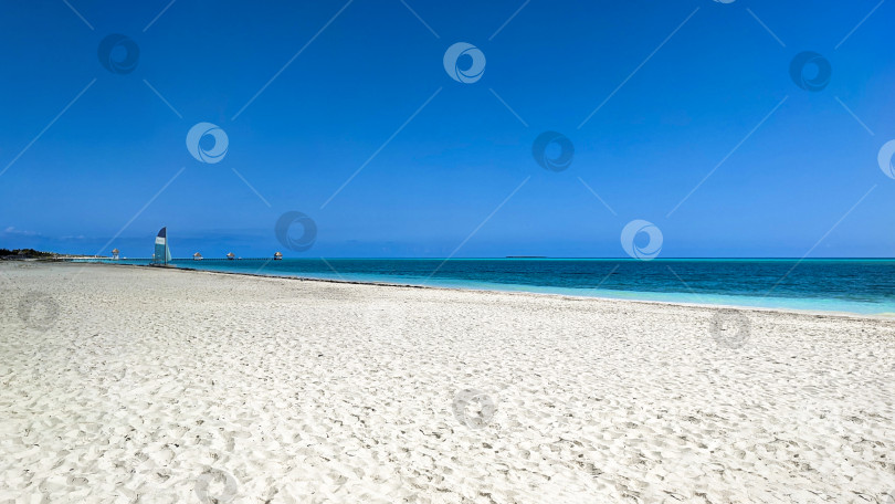 Скачать Белый песчаный пляж, пустынный берег вдоль лазурного океана, море с голубым небом и парусником. Фотография тропических морских пейзажей в горизонтальном формате для туризма, обоев, фона, социальных сетей. Куба, Кайо-Коко фотосток Ozero