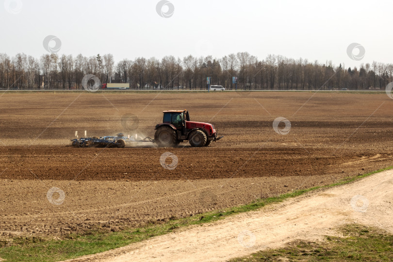 Скачать Красный трактор вспахивает поле крупным планом фотосток Ozero