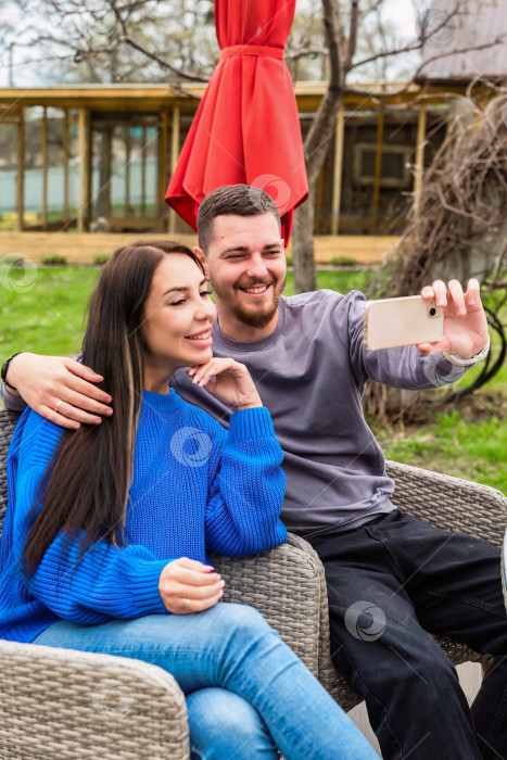 Скачать Молодая супружеская пара делает селфи и смеется на заднем дворе своего дома фотосток Ozero