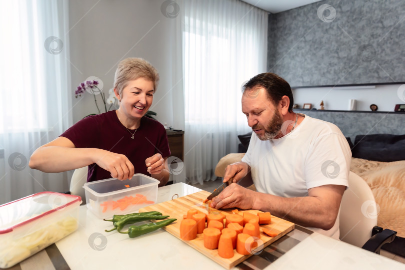 Скачать Зрелые русские муж и жена вместе готовят плов на кухне у себя дома фотосток Ozero