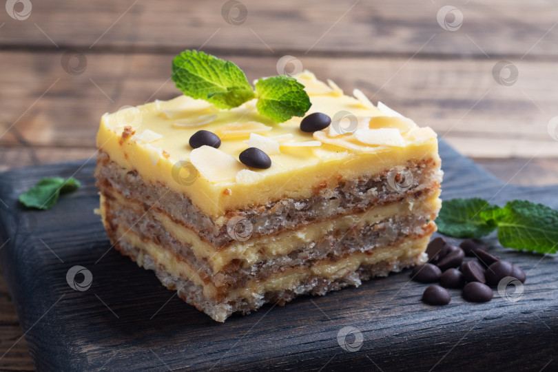 Скачать Банановый бисквитный торт с орехами и шоколадными каплями. Вкусный сладкий десерт к чаю на деревянном фоне. фотосток Ozero