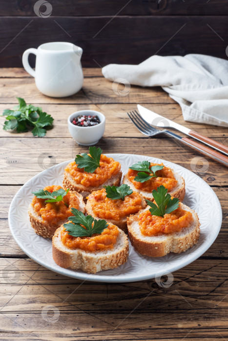 Скачать Бутерброды с хлебом, кабачковой икрой, помидорами и луком. Вегетарианские блюда домашнего приготовления. Консервированные тушеные овощи. деревянный фон фотосток Ozero