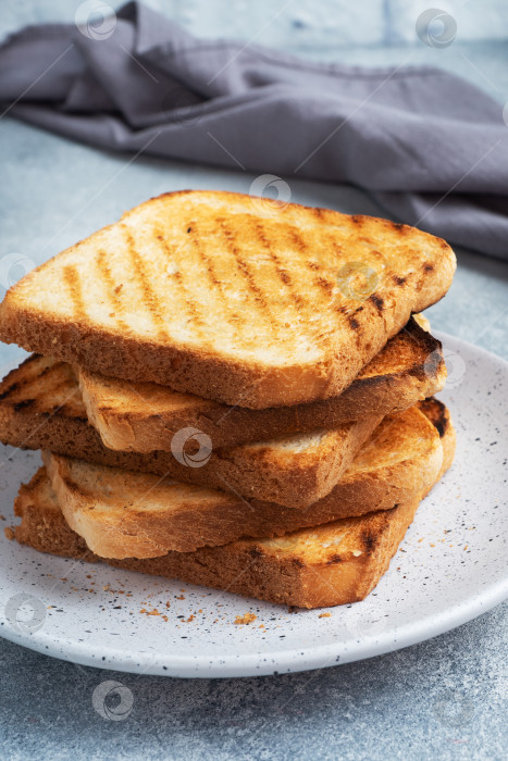 Скачать Поджаренный хлеб с хрустящей корочкой для бутербродов лежит на тарелке на сером бетонном столе. фотосток Ozero