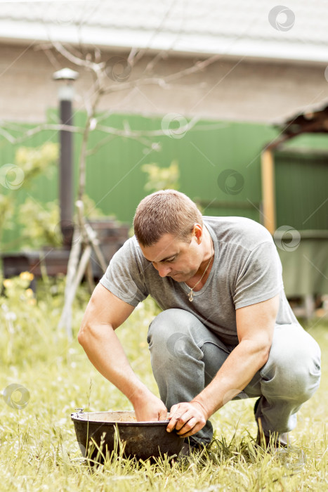Скачать Мужчина делает свою домашнюю работу, чистит котел на заднем дворе загородного дома фотосток Ozero