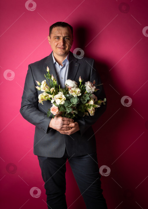 Скачать красивый бизнесмен в костюме смотрит в камеру с букетом цветов. фотосток Ozero