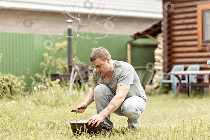 Скачать Мужчина делает свою домашнюю работу, чистит котел на заднем дворе загородного дома фотосток Ozero