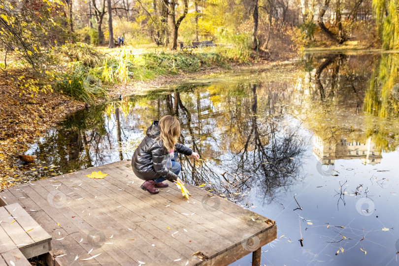 Скачать Молодая женщина на берегу пруда в осеннем парке фотосток Ozero