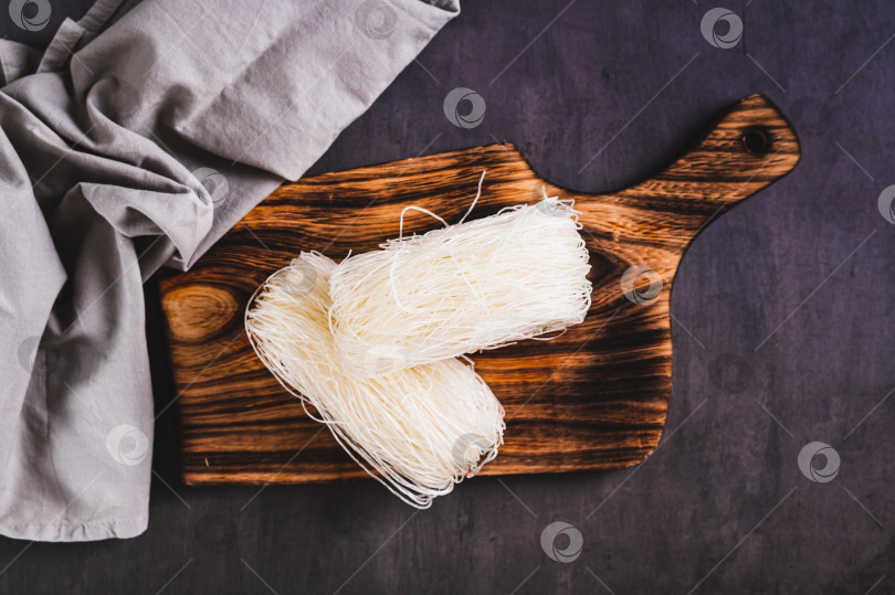 Скачать Крупный план азиатской рисовой лапши фунчозе на деревянной доске на столе вид сверху фотосток Ozero