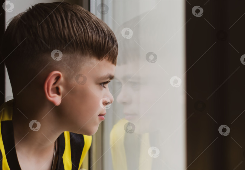 Скачать Маленький мальчик выглядывает из окна своей комнаты фотосток Ozero