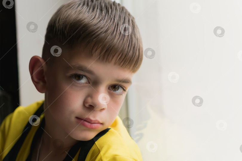 Скачать Маленький мальчик выглядывает из окна своей комнаты фотосток Ozero