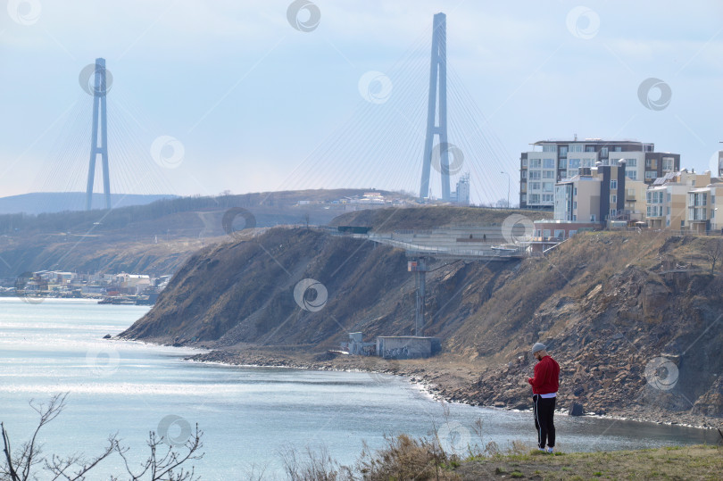 Скачать Мужчина в ярко-красной куртке стоит на пустынном утесе залива Патрокла (Patrokl) фотосток Ozero