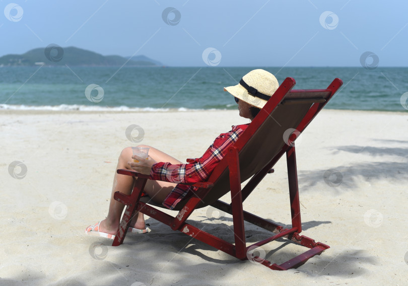 Скачать Молодая женщина пьет пиво и сидит в шезлонге на пляже в Нячанге фотосток Ozero