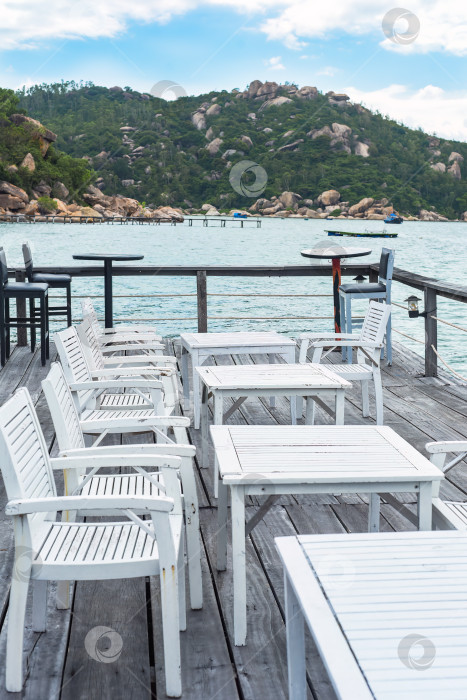 Скачать Белые деревянные стулья и столы на деревянном пирсе Южно-Китайского моря во Вьетнаме фотосток Ozero