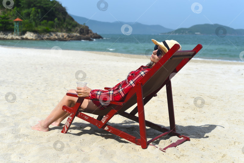 Скачать Молодой человек пьет пиво и сидит в шезлонге на пляже в Нячанге фотосток Ozero