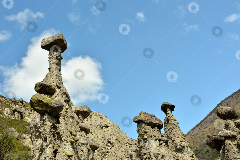 Скачать Вид снизу на высокие и необычные каменные образования на склоне высокой горы в солнечный весенний день. фотосток Ozero