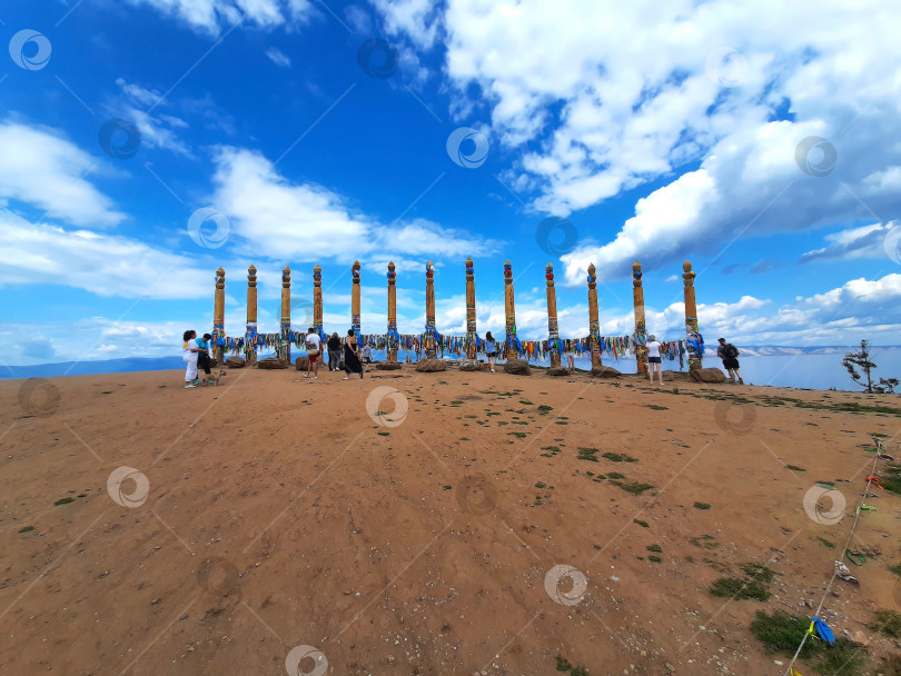 Скачать Российские туристы возле столбов с лентами религии шаманизм в Хужире, остров Ольхон. фотосток Ozero