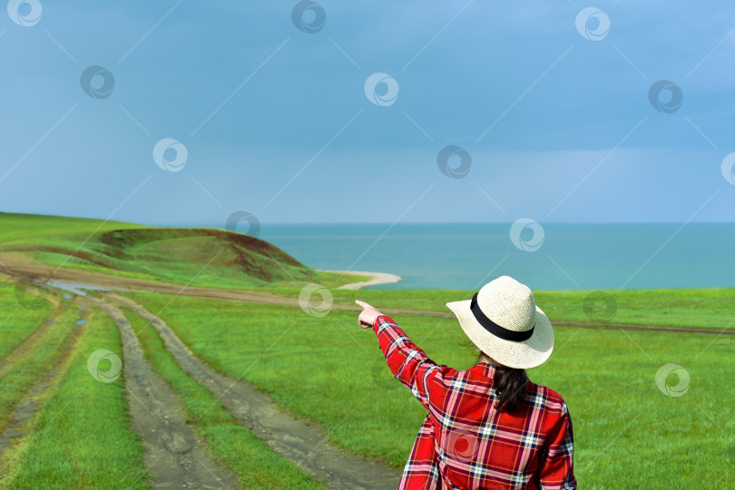 Скачать Молодая девушка в красной рубашке указывает пальцем на тропинку, ведущую к мысу Харанцы фотосток Ozero