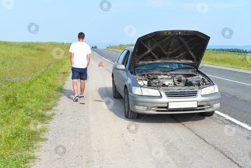 Скачать Грустный мужчина возле разбитой машины ищет помощи в полевых условиях фотосток Ozero
