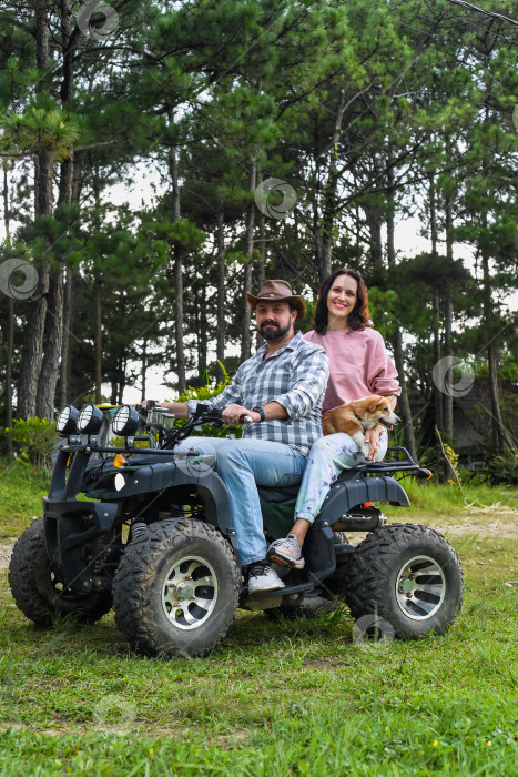 Скачать Портрет молодой супружеской пары, сидящей на квадроцикле в лесу фотосток Ozero