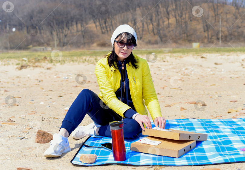 Скачать Русская 45-летняя женщина собирается съесть пиццу, сидя на пляже фотосток Ozero