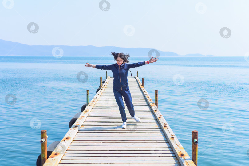 Скачать 45-летняя русская женщина бежит по деревянному пирсу на берегу Японского моря фотосток Ozero