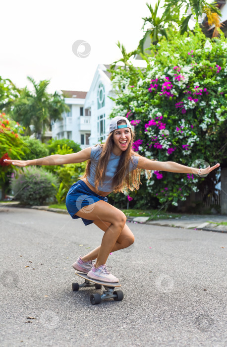 Скачать Молодая красивая женщина в кепке катается на скейтборде и смеется фотосток Ozero