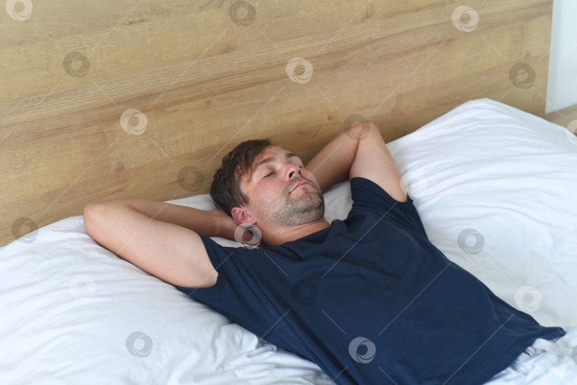 Скачать Молодой человек лежит на кровати и расслабляется фотосток Ozero