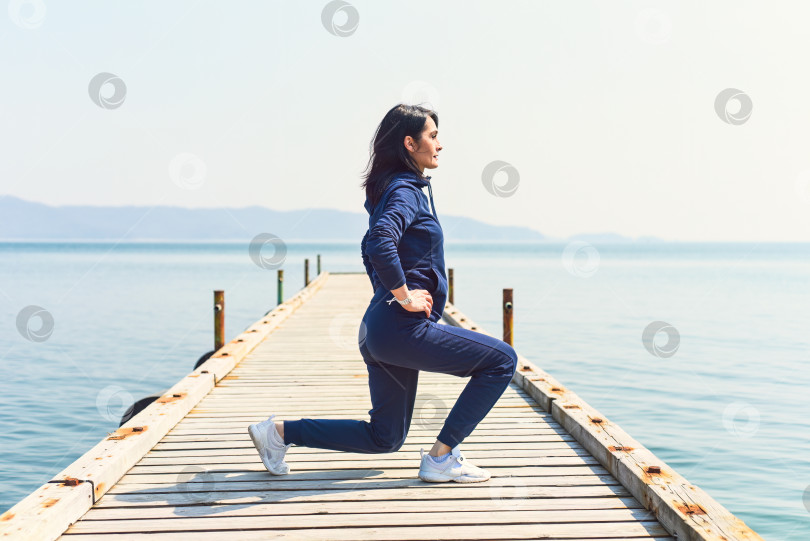 Скачать 45-летняя русская женщина сидит на корточках на деревянном пирсе на берегу Японского моря фотосток Ozero