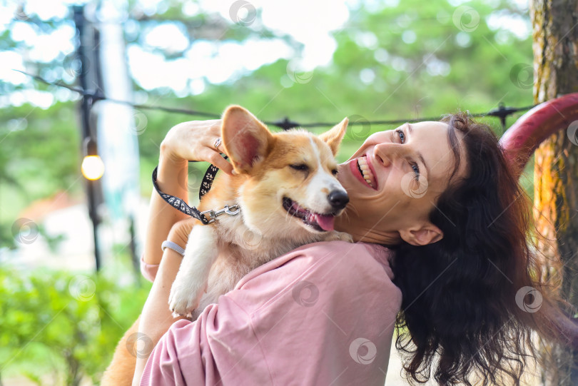 Скачать Молодая женщина обнимает свою собаку корги в лесу фотосток Ozero