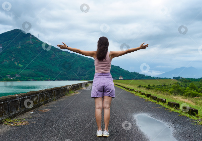Скачать Молодая русская путешественница с распростертыми объятиями у озера и гор в провинции Кханьхоа, Вьетнам фотосток Ozero