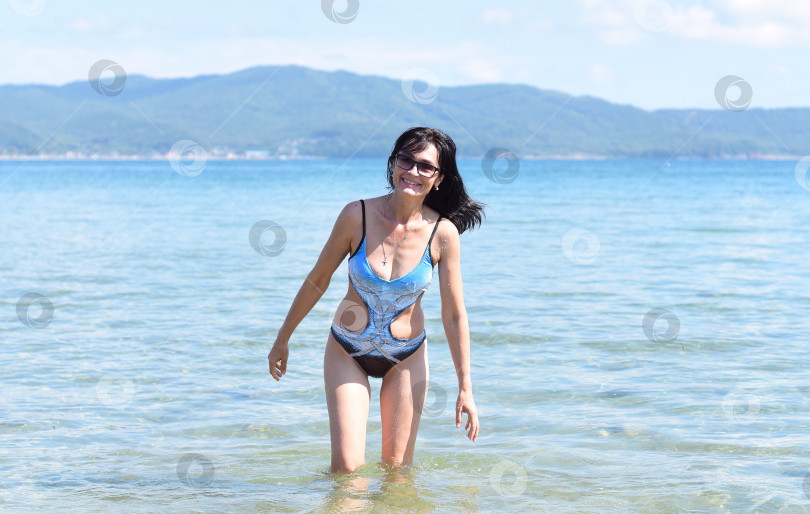 Скачать 45-летняя русская женщина в купальнике смеется и стоит в Японском море фотосток Ozero