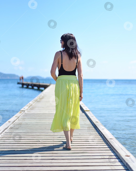 Скачать 45-летняя русская женщина прогуливается по пирсу на фоне Японского моря фотосток Ozero