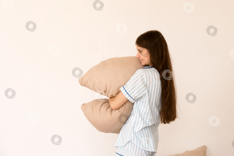 Скачать Подросток держит подушку и улыбается в игривом настроении. фотосток Ozero
